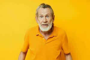 Senior grauhaarig Mann Gelb Hemd posieren Emotionen isoliert Hintergrund foto