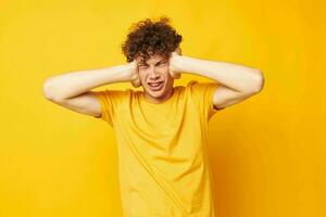Porträt von ein jung lockig Mann Gelb T-Shirt Mode Hand Gesten isoliert Hintergrund unverändert foto