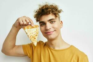 gut aussehend jung Mann im ein Gelb T-Shirt Essen Pizza Lebensstil unverändert foto