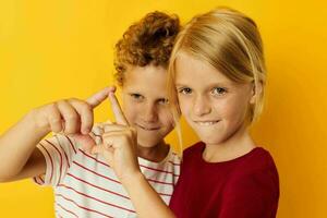 süß stilvoll Kinder Stehen Seite durch Seite posieren Kindheit Emotionen Gelb Hintergrund foto