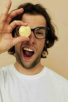 gut aussehend Mann mit Brille Gold Bitcoin im Hände isoliert Hintergrund foto