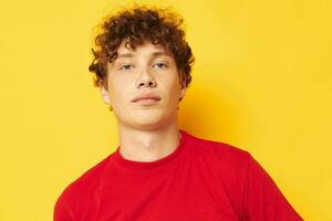 Porträt von ein jung lockig Mann Emotionen rot T-Shirt Hut Studio Gelb Hintergrund unverändert foto