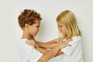 Foto von zwei Kinder im Weiß T-Shirts sind Stehen Nächster zu Beige Hintergrund