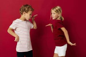 Porträt von süß Kinder Emotionen Stand Seite durch Seite im täglich Kleider rot Hintergrund foto