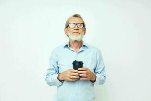Senior grauhaarig Mann Gesten mit seine Hände ein Glas von trinken Licht Hintergrund foto