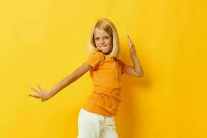wenig Mädchen Lächeln Hand Gesten posieren beiläufig tragen Spaß Gelb Hintergrund unverändert foto