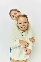 zwei wenig Mädchen im Pullover posieren Kindheit Licht Hintergrund foto