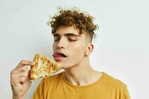 gut aussehend Kerl im ein Gelb T-Shirt Essen Pizza isoliert Hintergrund foto