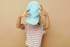 wenig Mädchen im Blau Kappen gestreift T-Shirt Emotionen Lebensstil unverändert foto