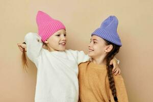 zwei komisch Mädchen umarmen posieren bunt Hüte foto