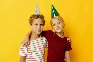 süß Vorschule Kinder Urlaub Spaß mit Kappen auf Ihre Kopf Gelb Hintergrund foto