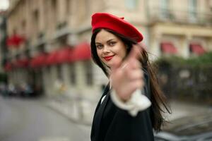 Mode Frau Lächeln mit Zähne Stehen auf das Straße im Vorderseite von das Stadt Tourist Folgen mich stilvoll Kleider mit rot Lippen und rot Baskenmütze, reisen, filmisch Farbe, retro Jahrgang Stil, städtisch Mode. foto