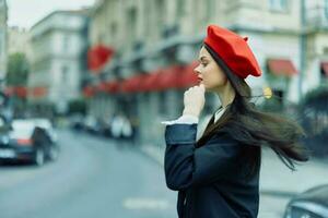 Mode Frau Porträt Schönheit Stehen auf das Straße im Vorderseite von das Stadt im stilvoll Kleider mit rot Lippen und rot Baskenmütze, reisen, filmisch Farbe, retro Jahrgang Stil, städtisch Mode Lebensstil. foto