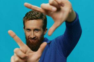 Porträt von ein Mann im ein Sweatshirt Lächeln und Glück, Hand Zeichen und Symbole, auf ein Blau Hintergrund. Lebensstil positiv, Kopieren Ort. foto