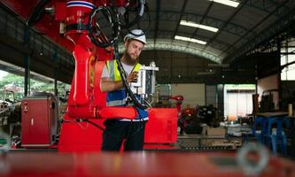ein Ingenieure Installation und testen ein groß Roboter Arm. Vor Senden es zu Kunden zum verwenden im das Industrie foto
