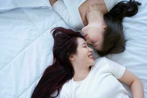 auf ein Weiß Bett, ein lgbt Paar ist sanft küssen jeder Andere Stirnen. foto