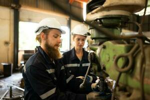 beide von mechanisch Ingenieure sind Überprüfung das Arbeiten Bedingung von ein alt Maschine Das hat gewesen benutzt zum etwas Zeit. im ein Fabrik wo natürlich Licht scheint auf zu das Arbeitsplatz foto