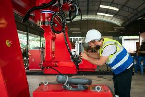 ein Ingenieure Installation und testen ein groß Roboter Arm. Vor Senden es zu Kunden zum verwenden im das Industrie foto