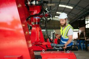 ein Ingenieure Installation und testen ein groß Roboter Arm. Vor Senden es zu Kunden zum verwenden im das Industrie foto