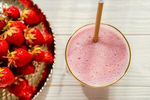 frisch Milchshake oder Smoothie im Glas mit Erdbeeren auf hölzern Tisch, schließen oben foto