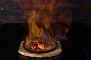 Fajitos, Fleisch in einer Pfanne mit Feuer auf einem Holztablett, schöne Portion, dunkler Hintergrund foto