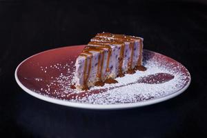 süßer Dessertkuchen auf einem Teller, schöne Portion, dunkler Hintergrund foto