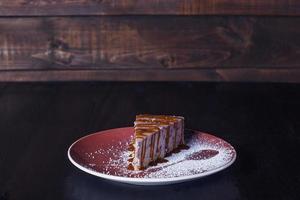 süßer Dessertkuchen auf einem Teller, schöne Portion, dunkler Hintergrund foto
