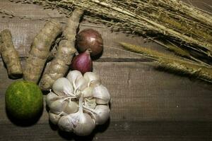 Knoblauch und rot Zwiebel, Union, Kurkuma , Limette Innerhalb ein gewebte Bambus Box auf hölzern Hintergrund foto