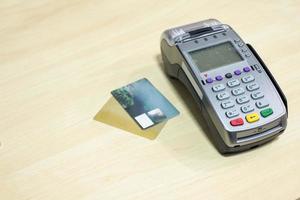 Kreditkarte mit Zahlungsterminal auf Holzschreibtisch foto