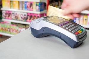 Hand durchziehen der Kreditkarte am Zahlungsterminal im Geschäft foto