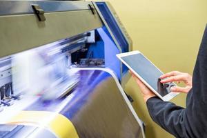 Techniker mit Tablet-Steuerung mit großformatigem Tintenstrahldruck blaues Vinyl foto