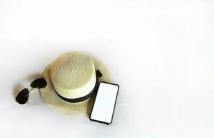 Ferien oder Wochenende und Reise mit oben Aussicht von Smartphone spotten oben zum hinzufügen oder füllen Text oder Bild, Weiß Jahrgang Hut und schwarz Sonnenbrille isoliert auf Weiß Hintergrund mit Kopieren Raum. entspannen Zeit foto
