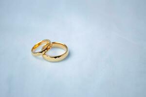 golden Hochzeit Ringe zum Engagement. Ehe golden Ringe mit Weiss, Rosa Bänder Hintergrund. Ringe auf das Weiß und rot Rose. das Ehe Ringe ist das Symbol von traditionell Hochzeit von Paar Liebhaber. foto