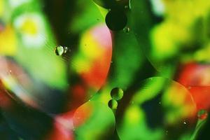 ein schönes und farbenfrohes Makro von Ölblasen auf dem Wasser mit einer grünen, roten und schwarzen Blumenstruktur als Hintergrundmuster mit einem Vintage-Filter foto