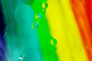 ein schönes und farbenfrohes Makro von Ölblasen auf dem Wasser mit einer gelben, roten, grünen, orangefarbenen und blauen Streifenstruktur als Hintergrundmuster foto