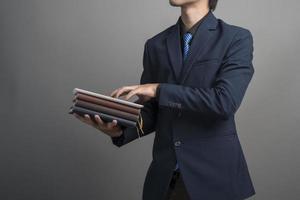Nahaufnahme eines Geschäftsmannes im blauen Anzug mit Büchern auf grauem Hintergrund holding foto
