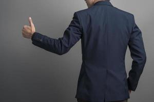 Nahaufnahme von Geschäftsmann im blauen Anzug Daumen hoch auf grauem Hintergrund foto