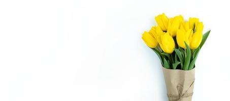 Strauß gelber Tulpen, eingewickelt in Kraftpapier auf weißem Hintergrund mit Kopierraum. foto