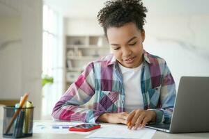 konzentriert biracial Teen Mädchen Studien beim Zuhause Laptop, Hausaufgaben, Prüfung Vorbereitung. Umarmen Entfernung Bildung. foto