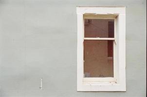altes Fenster an einem grauen Gebäude foto