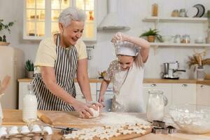 glücklich Familie im Küche. Oma und Enkelin Kind Koch im Küche zusammen. Oma Lehren Kind Mädchen kneten Teig backen Kekse. Haushalt Zusammenarbeit Portion Familie Generationen Konzept. foto