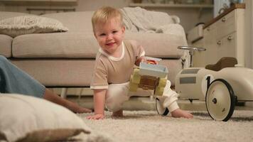 glücklich Familie beim heim. Baby Junge spielen mit Spielzeuge beim Zuhause drinnen. wenig Kleinkind Kind und Mutter haben Spaß zusammen. Kind Sohn sich ausruhen im Leben Zimmer. foto