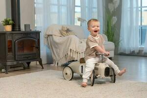 glücklich Kind beim heim. wenig Kleinkind Junge Fahren groß Jahrgang Spielzeug Auto und haben Spaß. lächelnd Kind spielen beim heim. Baby Junge spielen mit Spielzeug im Leben Zimmer drinnen. foto