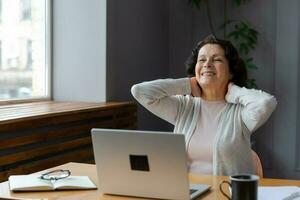 Mitte alt Senior Frau berühren Tempel erleben Stress im Büro. älter reifen Führer Boss müde von Arbeiten Gefühl Kopfschmerzen krank. lange Laptop Verwendungszweck Computer Vision Syndrom. Büro Syndrom. foto