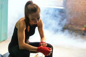 Frauen selbst Verteidigung Mädchen Leistung. Frau Kämpfer vorbereiten zum Kampf Verpackung Hände mit rot Boxen Wraps Sport schützend Bandagen. stark Mädchen bereit zum Kampf aktiv Übung Sparring trainieren Ausbildung. foto