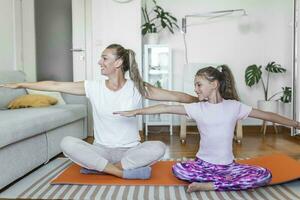 heiter passen weiblich und wenig Tochter tun Ausfallschritte Übungen während Ausbildung zusammen im Vorderseite von Laptop im modern Wohnung. Familie Mutter und Kind Tochter sind beschäftigt, verlobt im Fitness foto