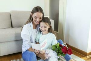 glücklich Mutter Tag. Kind Tochter gratuliert Mama und gibt ihr Postkarte und Blumen. Mama und Mädchen lächelnd und umarmen. Familie Urlaub und Zusammengehörigkeit. foto