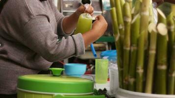 das Hände von ein indonesisch Straße Verkäufer vorbereiten ein Glas von Zucker Stock Saft. foto