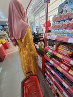 Jakarta, Indonesien im März 2023. ein Mutter tragen ein Gelb Neglige ist bezahlen beim das Alfamart Kassierer. foto