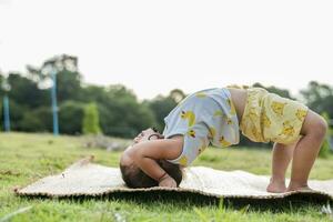 Mädchen tun Gymnastik auf ein Fitness Matte einsam beim Zuhause tun Yoga tun Brücke natürlich zurück Kurve flexibel Kinder tun Gymnastik- Übungen. Sport, Lernen, Fitness, dehnen, aktiv Lebensstil Konzept. foto